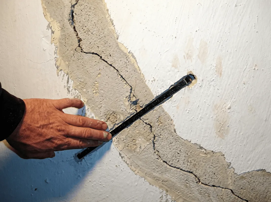 A wall with a large crack is being inspected by a professional in Honolulu, HI